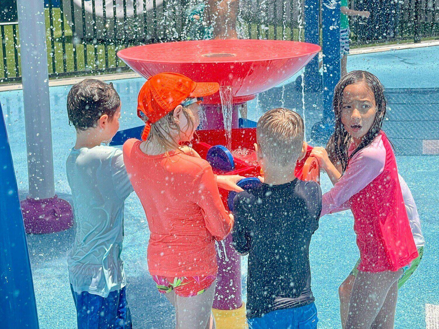 children gathered around a water play table